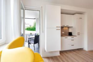 a living room with a yellow chair and a kitchen at Modernes Apartment *Liobablick Nr. 4* - FeWo in Fulda/Petersberg in Petersberg