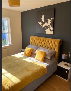 a bedroom with a large bed with yellow pillows at A Bigger Splash -Apartment Bangor West in Bangor