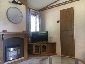 a living room with a clock over a fireplace and a tv at Domek na Trylkówku in Szczytno