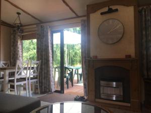 a living room with a fireplace and a clock on the wall at Domek na Trylkówku in Szczytno