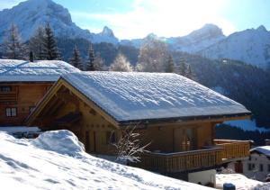 een huis bedekt met sneeuw met bergen op de achtergrond bij Chalet Forget me not in Gryon