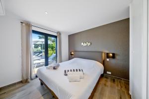 a bedroom with a large white bed and a large window at Résidence Pierre & Vacances Premium Les Terrasses d'Arsella in Porto-Vecchio