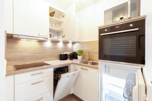 een keuken met witte kasten en een zwart apparaat bij Modernes Apartment *Liobablick Nr. 3* - FeWo Fulda/Petersberg in Petersberg