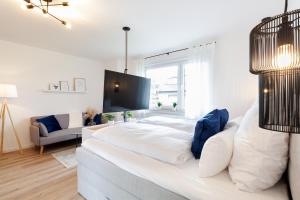 een groot wit bed in een kamer met een bank bij Modernes Apartment *Liobablick Nr. 3* - FeWo Fulda/Petersberg in Petersberg
