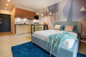 a bedroom with a blue bed and a kitchen at W&K Apartments - Joy Suite - Faktura VAT, Parking in Koszalin