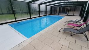 a swimming pool with two chairs and a table at Gite de la Bourbatte in Gerbamont 