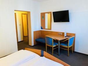 a room with a bed and a table and a tv at Pension Marktplatz Rüsselsheim in Rüsselsheim