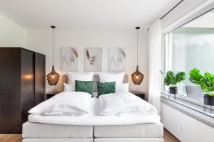 a white bedroom with a large white bed with green pillows at Modernes Apartment *Liobablick Nr. 2* - FeWo in Fulda/Petersberg in Petersberg