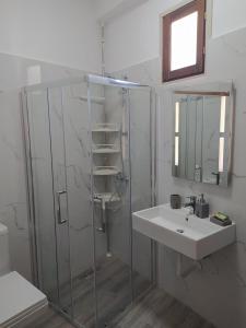 La salle de bains est pourvue d'une douche en verre et d'un lavabo. dans l'établissement A&Fabio Guesthouse, à Gjirokastër