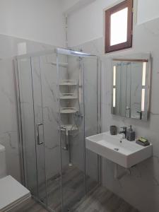 a bathroom with a glass shower and a sink at A&Fabio Guesthouse in Gjirokastër