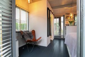 a bedroom with a bed and a chair in a room at Tiny House Boatshed in Heemstede