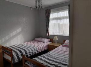 2 camas individuales en un dormitorio con ventana en alicias chalets, en Great Yarmouth