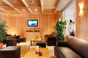 a living room filled with furniture and a tv at Hotel Auwirt Zentrum in Saalbach-Hinterglemm