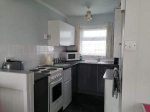 uma cozinha com armários brancos e um forno com placa de fogão em alicias chalets em Great Yarmouth