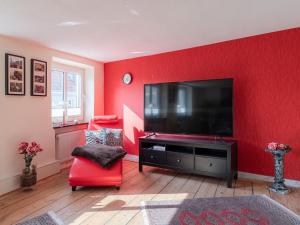 a living room with a red wall with a flat screen tv at InselGlueck in Herzen Malchows in Malchow