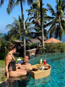 Un uomo e una donna seduti in piscina di Puri Dajuma Beach Eco-Resort & Spa a Pulukan