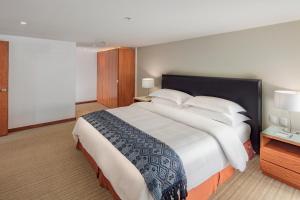 una camera da letto con un grande letto con lenzuola e cuscini bianchi di Presidente Intercontinental Puebla, an IHG Hotel a Puebla