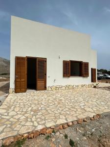 een wit gebouw met 2 deuren en een stenen patio bij Aria case vacanze in Favignana