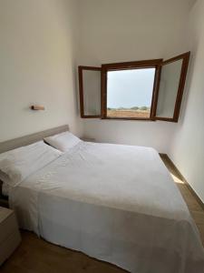 een wit bed in een kamer met een raam bij Aria case vacanze in Favignana