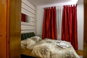a bed in a room with red curtains and a window at Silver in Žarkovo