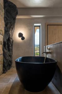 a large black bath tub in a bathroom with a window at Acro Suites - A Wellbeing Resort in Agia Pelagia