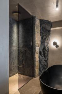 a bathroom with a black tub and a stone wall at Acro Suites - A Wellbeing Resort in Agia Pelagia