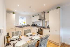 a kitchen with a table and chairs and a kitchen with white cabinets at Stylish & Modern Apartment in Inverness