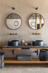 two mirrors on the wall above a counter with two sinks at Acro Suites - A Wellbeing Resort in Agia Pelagia