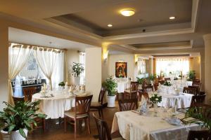 un ristorante con tavoli e sedie bianchi e piante di First Hotel ad Ho Chi Minh