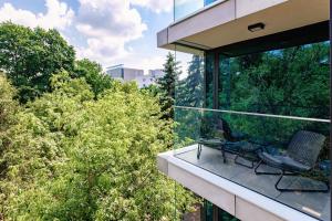 Un balcón con 2 sillas y árboles en un edificio en Apartamenty Premium NJ Lublin Centrum Basen & SPA, en Lublin
