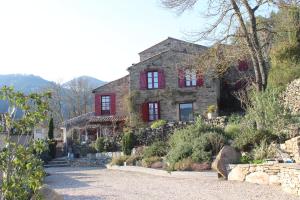 una vecchia casa di pietra con finestre rosse su una collina di Le Pailler de la Planque a Camplong