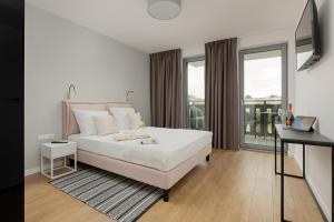 Habitación blanca con cama y balcón. en Apartamenty Gryf Rewal en Rewal