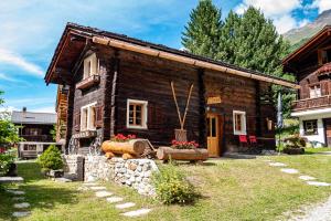 una casa di tronchi con un giardino di fronte di Izba a Zinal