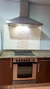 a stove top oven in a kitchen with a hood at Apartamento Loft III Select Real Caldas de Reis in Caldas de Reis