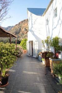 a walkway next to a white building with plants at Kogman & Keisie Guest Farm in Montagu