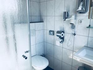 a bathroom with a shower with a toilet and a phone at Pension Marktplatz Rüsselsheim in Rüsselsheim