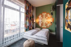 a bedroom with a bed and a large window at Superbude Hamburg Altona in Hamburg