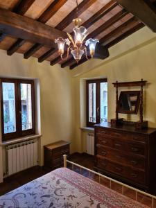 ein Schlafzimmer mit einem Bett, einer Kommode und einem Kronleuchter in der Unterkunft Casa vacanze Torre dell'orologio in Montefalco