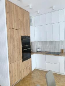 a kitchen with white cabinets and a black oven at Apartamenty na skraju lasu in Ustka