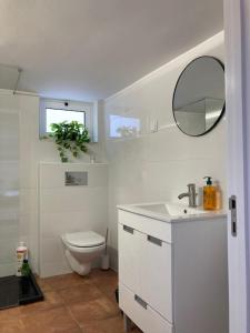 een witte badkamer met een toilet en een spiegel bij Beautiful Boutique House Near the Beach in Costa da Caparica