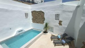 a swimming pool in a white room with chairs and a plant at Buena Vista Ronda Club in Ronda