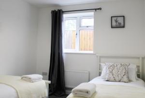 1 dormitorio con 2 camas y ventana en Didcot - Private Flat with Garden & Parking 08, en Didcot
