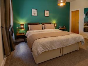 a bedroom with a large bed with a green wall at The Old Cross Inn in Blairgowrie
