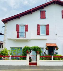 una casa blanca con persianas rojas y una valla roja en Appartement neuf et moderne, en Saint-Palais