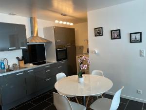 cocina con mesa blanca y sillas blancas en Appartement neuf et moderne, en Saint-Palais
