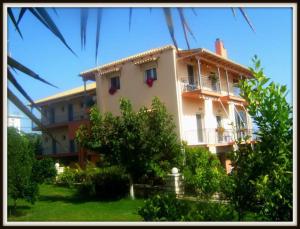 a large white building with a balcony and trees at Αλκυονη Διαμερισματα in Paralia Vrachou