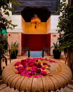 una gran mesa de madera con flores rosas. en Riad Dar Jaguar, en Marrakech