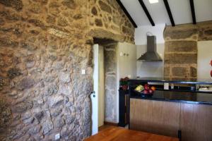 uma cozinha com uma parede de pedra com um balcão e um lavatório em Casa das Saras em Gonçalo