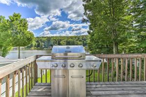 a grill on a wooden deck next to a lake at Acre Lake Chalet, 12 Mi to Elk Mountain Ski Resort in Kingsley