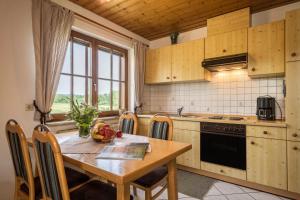 a kitchen with a wooden table and a table and chairs at Hof Wagenberg Ferienwohnung 1 in Deggenhausertal